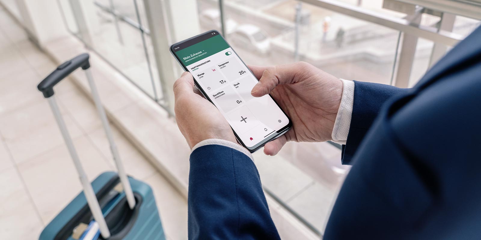 Eine Person in einem Anzug hält ein Smartphone und überprüft die Temperatur und Luftfeuchtigkeit in einem modernen Raum.