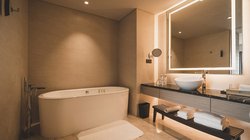 Ein modernes Badezimmer mit einer freistehenden Badewanne, eleganten Fliesen und einem stilvollen Waschbecken auf einem Holzregal.