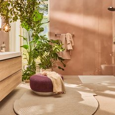 Ein modernes Badezimmer mit sanften Erdtönen, Pflanzen und einem eleganten Waschbecken aus Holz und Weiß.